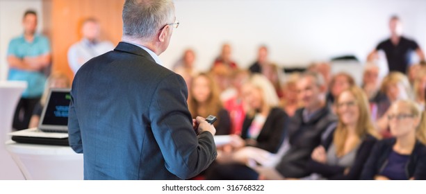 Speaker At Business Conference With Public Presentations. Audience At The Conference Hall. Entrepreneurship Club. Rear View. Horisontal Composition. Background Blur.