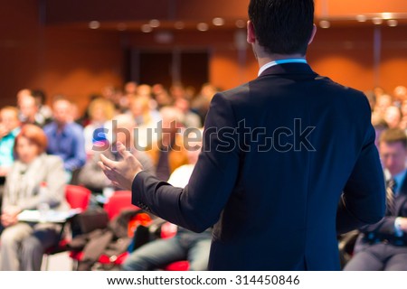 Speaker at Business Conference with Public Presentations. Audience at the conference hall. Entrepreneurship club. Rear view. Horisontal composition. Background blur.