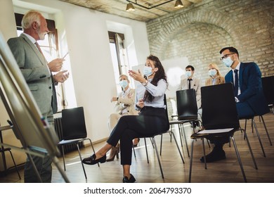 Speaker At Business Workshop And Presentation. Audience With Protective Mask At The Conference Room.