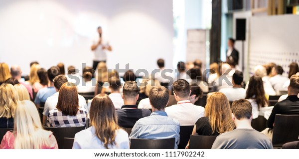 Speaker giving a talk\
in conference hall at business event. Audience at the conference\
hall. Business and Entrepreneurship concept. Focus on\
unrecognizable people in\
audience.