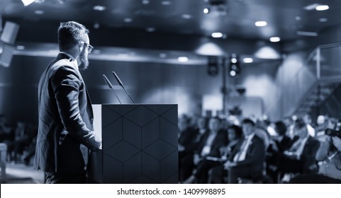 Speaker giving a talk on corporate business conference. Unrecognizable people in audience at conference hall. Business and Entrepreneurship event. Blue toned grayscale image. - Shutterstock ID 1409998895