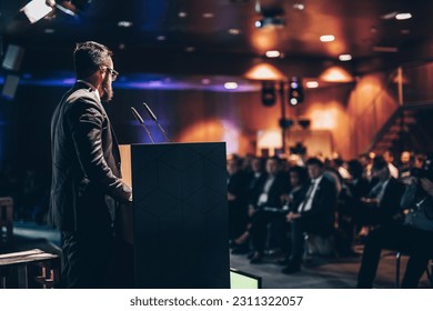 Speaker giving a talk on corporate business conference. Unrecognizable people in audience at conference hall. Business and Entrepreneurship event. - Shutterstock ID 2311322057