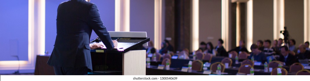 Speaker With Hands And Arms On Podium At Corporate Conference. Expert Lecture By Business Management At Hall. Leadership Symposium Event For Future Leaders.