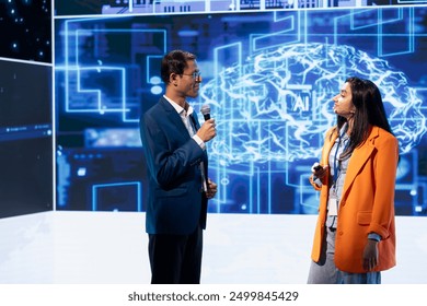 Speaker interviewing guest during presentation, exploring ways emerging AI technologies can enhance businesses. IT company colleagues at event present artificial intelligence tech - Powered by Shutterstock