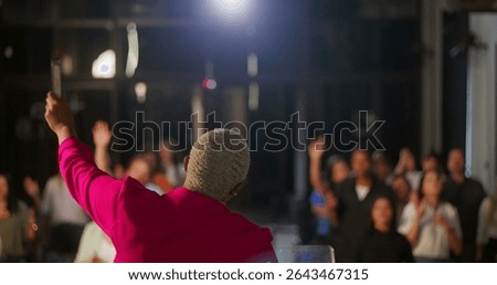 Speaker leading a congregation, back view, holding a Bible with hand raised, dynamic preaching, diverse audience in prayer and worship, indoor church setting, spiritual energy and connection