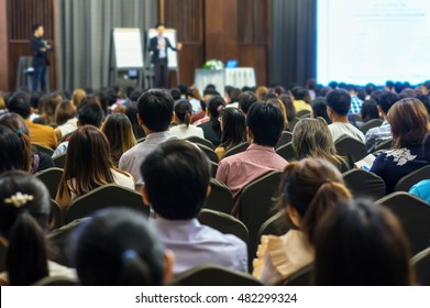 Speaker On The Stage With Rear View Of Audience In The Conference Hall Or Seminar Meeting, Business And Education Concept