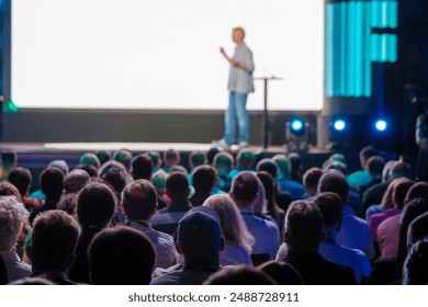 Speaker presents at a conference while a large audience listens attentively, fostering learning and engagement. - Powered by Shutterstock