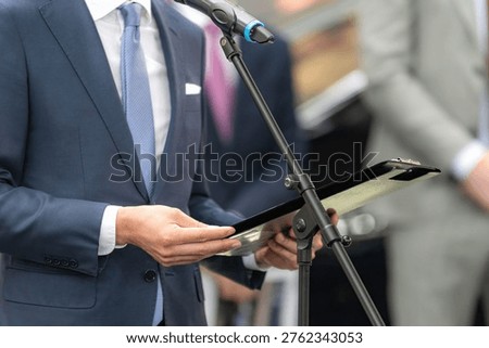 Speaker reading prepared notes while addressing an audience at a media conference. Structured delivery supports clarity, accuracy, and effective professional communication.