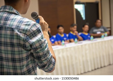 Speaker talking with mic presenting work in business meeting room.Close up microphone in speaker hand at conference seminar room with blur people in background.