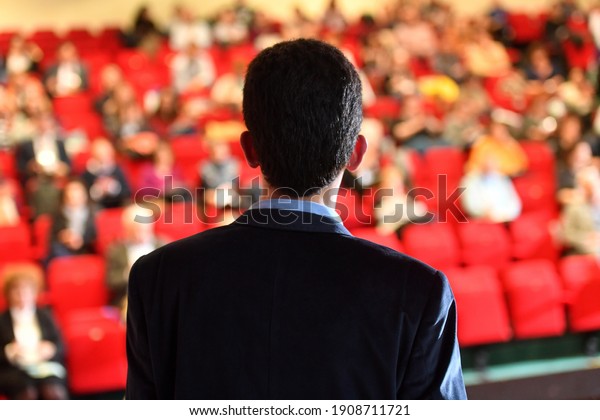  \
Speakers. The person speaking in front\
of a room, presentation.