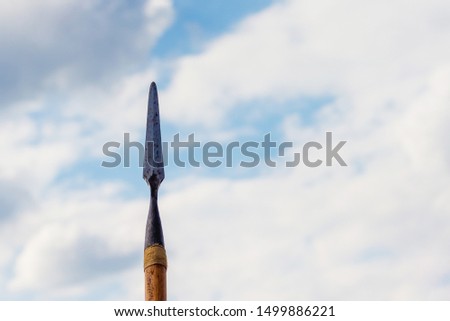 Spear on sky background. Cold weapons. A symbol of war and protection