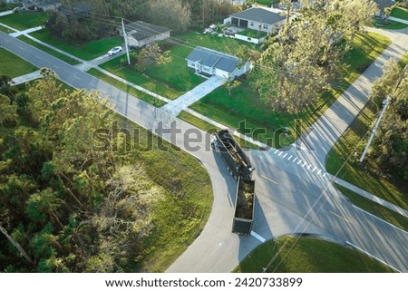 Special aftermath recovery dump truck picking up vegetation debris from suburban streets after hurricane Ian swept through Florida. Dealing with consequences of natural disaster