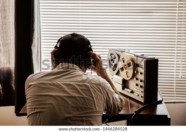 Special agent\
listens on the reel tape recorder. Officer wiretapping in\
headphones. KGB spying of\
conversations.