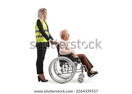 Special assitance worker standing behind a senior woman in a wheelchair isolated on white background