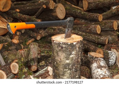 A special axe for splitting wood is stuck into the log. The axe splits the log for drying and subsequent preparation for heating scrap in winter.