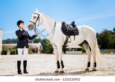 Special Clothes. Appealing Professional Female Rider With Long Braid Wearing Special Clothes Standing Near Horse