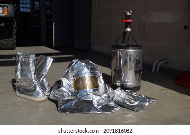 Special Clothing To Protect Firefighters From Heat Exposure And A Fire Barrel To Extinguish Flammable Liquids. Equipment Of A Firefighter At An Oil Refinery.