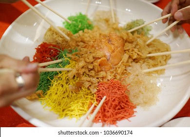 A special dish during Chinese New Year, Yusheng or Yee Sang. Chinese belief eating Yee Sang will bring good luck and prosperity. Motion blur to show hand and chopsticks movements.
