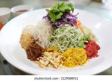 A special dish during Chinese New Year, Yusheng or Yee Sang. Chinese belief eating Yee Sang will bring good luck and prosperity. Motion blur to show hand and chopsticks movements. Soft focus image.