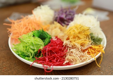 A special dish during Chinese New Year, Yusheng or Yee Sang. Chinese belief eating Yee Sang will bring good luck and prosperity. Motion blur to show hand and chopsticks movements. Soft focus image.