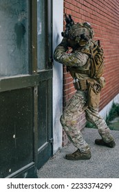 Special forces operator in Multicam uniform perform CQB tactics training in abandoned building. He carry his assault rifle HK416 and coyote plate carrier.