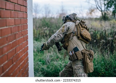 Special forces operator in Multicam uniform perform CQB tactics training in abandoned building. He carry his assault rifle HK416 and coyote plate carrier.