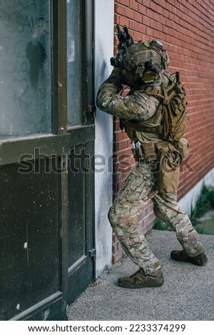 Special forces operator in Multicam uniform perform CQB tactics training in abandoned building. He carry his assault rifle HK416 and coyote plate carrier.
