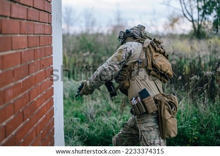 Special forces operator in Multicam uniform perform CQB tactics training in abandoned building. He carry his assault rifle HK416 and coyote plate carrier.