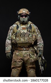 Special Forces Soldier Man In Military Gear, Protective Mask, Glasses And Mask Hiding His Face With Machine Gun Is Standing Straight Up, Looking At The Camera Isolated On A Black Background In Studio