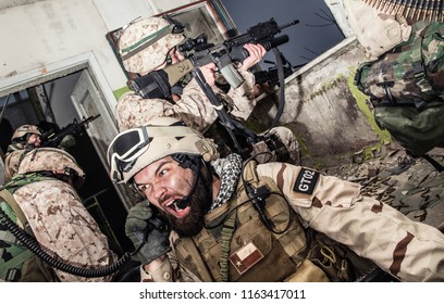 Special forces team leader screaming in tactical radio handset while coordinating allies actions, calling for reinforcements, requesting for artillery fire support under enemy fire during firefight