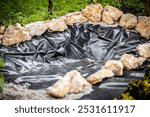 special liner for a pond in the garden, concept landscaping, new pond with limestones and pump with waterfall