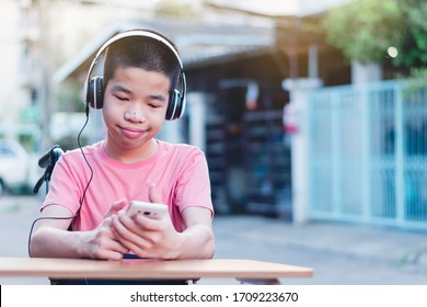 Special Need Child On Wheelchair Wearing Headphones And Happy Time To Use A Smartphone,Study And Work At Home For Safety From Covid 19, Life In The Education Age Of Special Need Kid,Sweet Boy Concept.