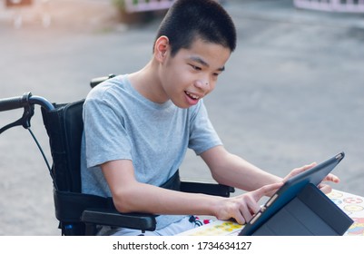 Special Need Child On Wheelchair Happy Time To Use A Tablet In The House, Study And Work At Home For Safety From Covid 19, Life In The Education Age Of Special Need Kid, Happy Disabled Boy Concept.