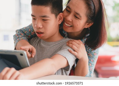 Special Need Child On Wheelchair Use A Tablet In The House With His Parent, Study Or Work At Home In Online Communication,Life In New Normal Education Of Special Need Kid,Happy Disabled Boy Concept.