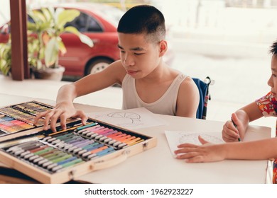 Special Need Child On Wheelchair Writing Practice In Home On Garden Nature Background,Life In Education Of Disabled Kid, Concept Of People Doing Art Hobbies With Home School And Happy Disability Boy.