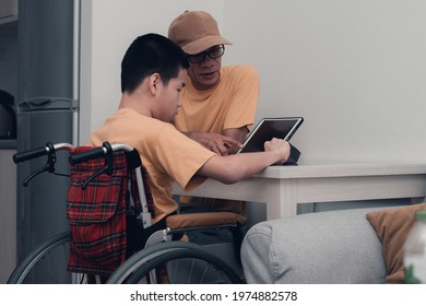 Special Need Child On Wheelchair Use A Tablet In The House With His Parent, Study Or Work At Home For Safety From Covid 19, Life In New Normal Education Of Special Need Kid,Happy Disabled Boy Concept.