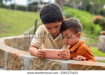 Special needs child and sibling engrossed in phone in natural setting