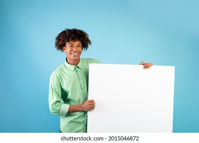 Special Offer. Happy Black Teen Guy Holding Empty Blank Board Over Blue Studio Background. Smiling Guy Standing With White Square Paper Placard For Ad, Showing It To Camera