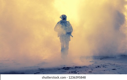 Special operations forces soldier, army ranger or commando in camo uniform, helmet and ballistic glasses walking at battlefield covered with smoke. Airsoft war game player coming through smoke screen