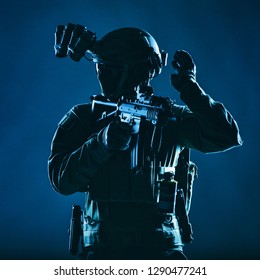 Special Operations Soldier, SWAT Team Fighter In Mask And Glasses, Equipped Night Vision Device, Armed Short Barrel Service Rifle, Looking Back And Showing Freeze Hand Signal, Low Key Studio Shoot