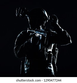 Special Operations Soldier, SWAT Team Fighter In Mask And Glasses, Equipped Night Vision Device, Armed Short Barrel Service Rifle, Looking Back And Showing Freeze Hand Signal, Low Key Studio Shoot