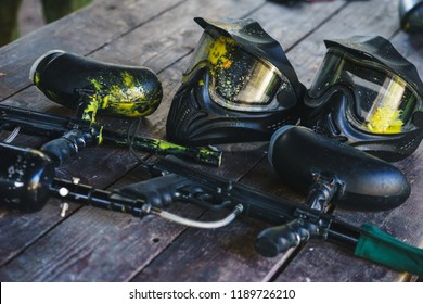 Special protective mask for playing paintball with traces and spot of hit of a ball with paint. Equipment for playing paintball on a wooden table. Game marker and a protective mask. Image photography.