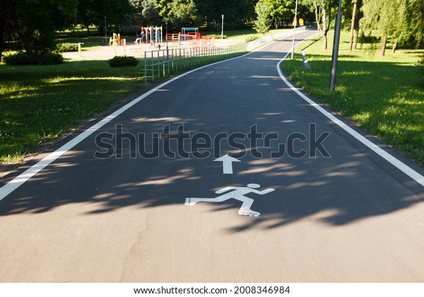 Special road\
for rollerblading, roller skate track. Sign of a man on rollers on\
the asphalt. No one in the\
park.