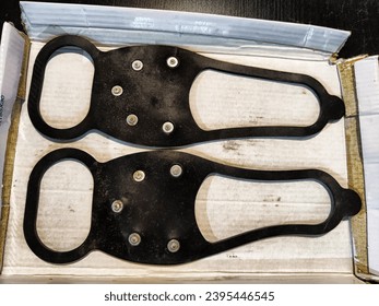 Special rubber tips with spikes on shoes to avoid slipping on ice in winter. Crampons and spices on our boots. Devices for moving on slippery sidewalks and roads. Concept of clothing and safety - Shutterstock ID 2395446545