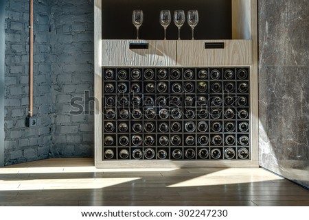 Special shelf for storing wine. Sunlight leaves light spot. Fragment of the interior in the style of a loft.