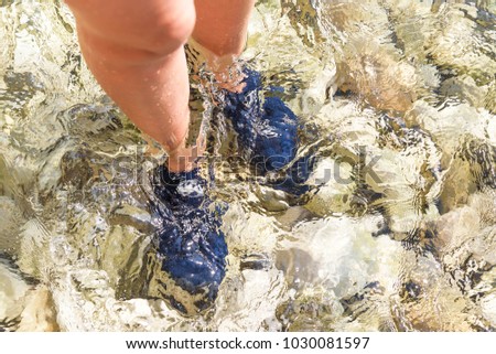 Special shoes for walking on the stones in the sea. Female feet close-up.
