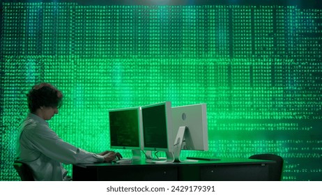 IT specialist against big digital screen. Man programmer engineer works on computer in front of screen with digital code data process.