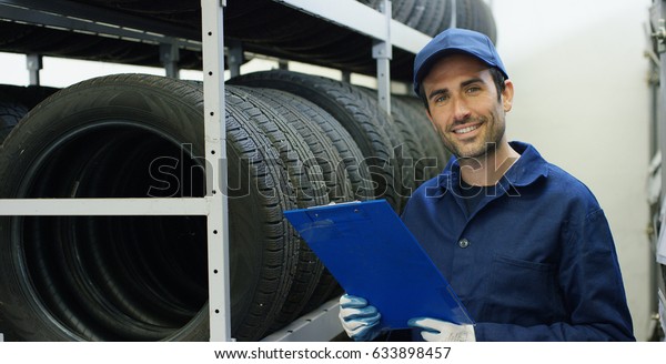 Specialist auto mechanic in the car service,\
checks the tire tread, in the background of rubber Concept repair\
of machines fault diagnosis repair specialist technical maintenance\
and on-board\
computer
