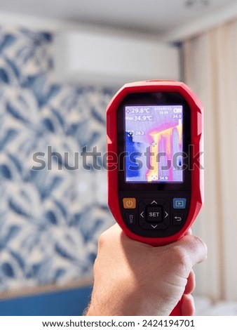 A specialist conducts a thermal imaging examination inside the building. Search for heat losses. Inspection of the walls of the room to eliminate deficiencies and insulate problem areas