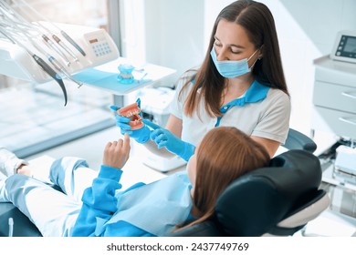 Specialist in a dental clinic teaches a child oral hygiene - Powered by Shutterstock